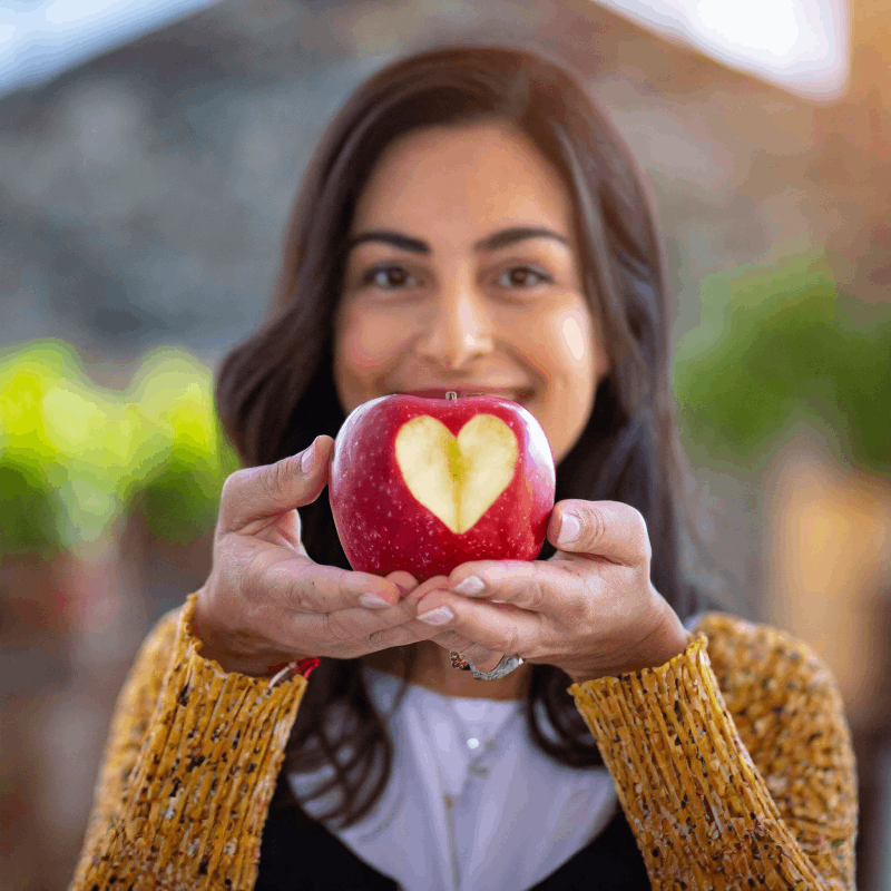 Donna_con_viso_sfocato_che_tiene_nelle_mani_una_mela_con_scavato_un_cuore_nella_polpa_69385.png